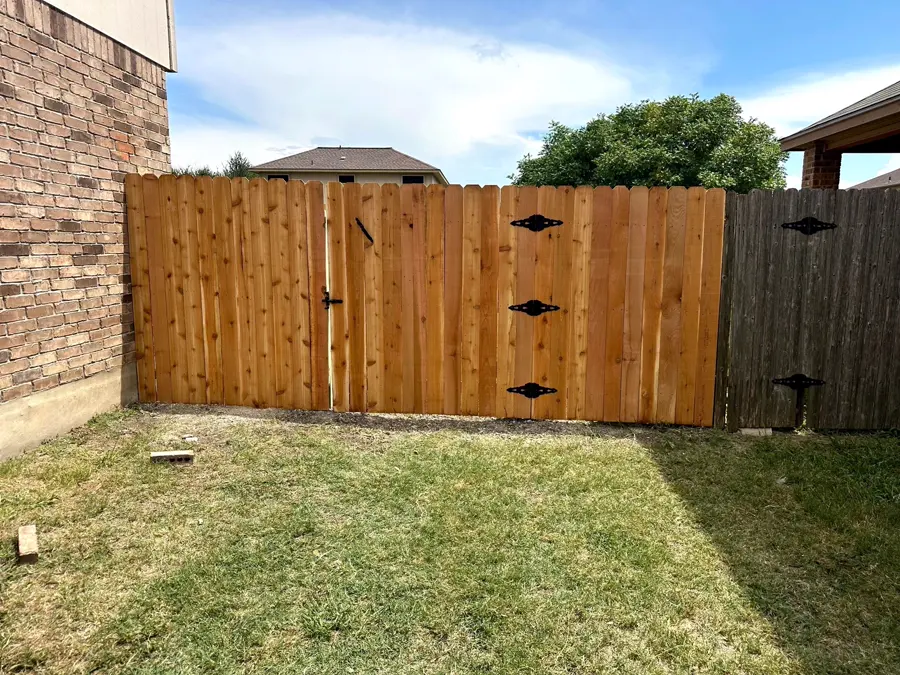New cedar privacy fence and gate beside a brick house