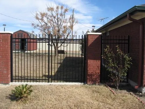Black ornamental gate between two brick columns