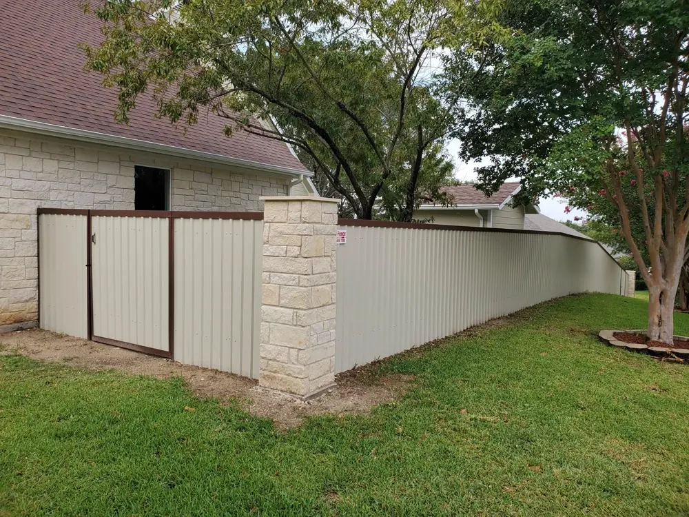 Cream metal privacy fence with a stone column and a walk gate